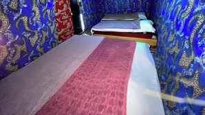 A narrow room with patterned walls, a bed, and a red curtain. - Campsite. Where you are you going to spend your nights in desert. (Merzouga)