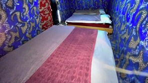 Une petite pièce avec un lit, un tapis à motifs rouges et blancs et des murs à motifs bleus.
