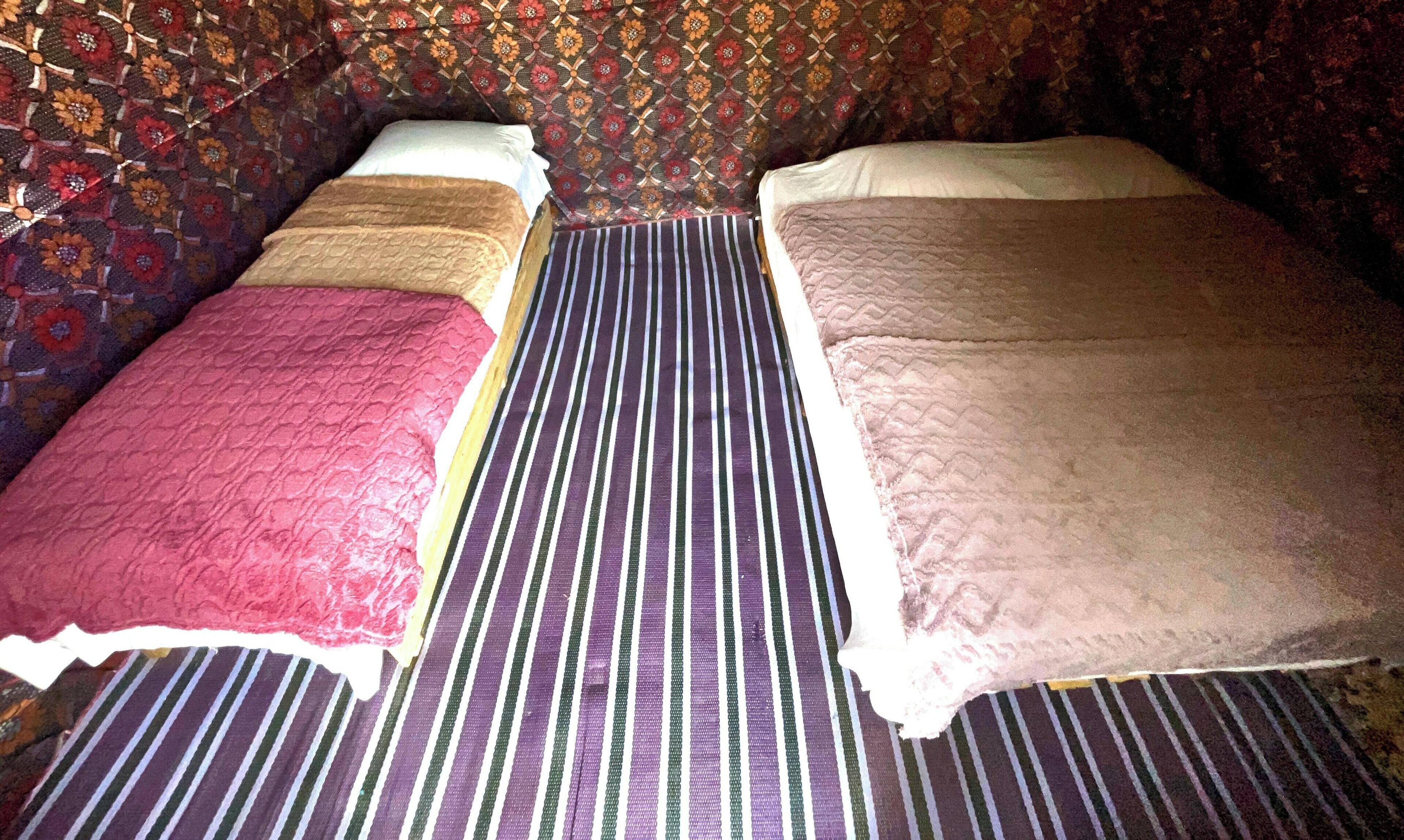 A room with two beds, a patterned wall, and a striped floor.