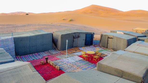 A desert camp with tents, colorful rugs, and a drum set. - Campsite. Where you are you going to spend your nights in desert. (Merzouga)