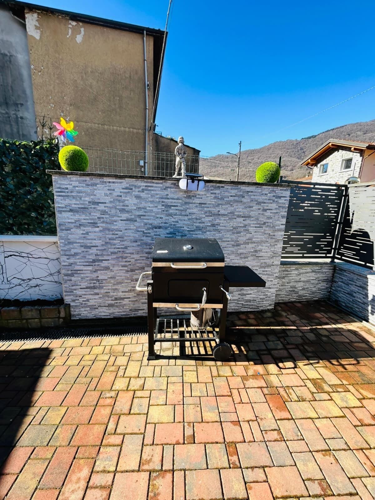 Un patio con una parrilla, un muro de piedra y una estatua.