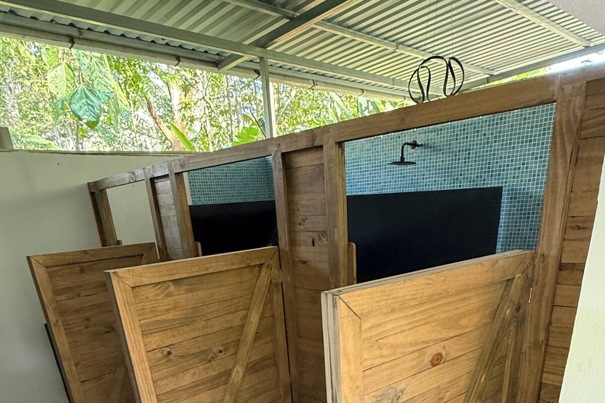 A room with wooden partitions, a tiled wall, and a metal roof.