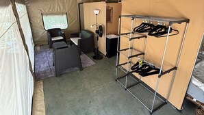 Ein Zelt mit Etagenbett, einem Stuhl, einem Schreibtisch, einer Lampe und einem Ventilator.