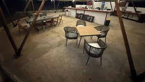 Ein Essbereich im Freien mit Zeltdach, Tischen, Stühlen, einer Bar und einem Kühlschrank.