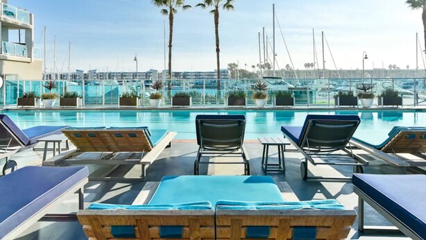 Un espace piscine avec des chaises longues et vue sur le port de plaisance.