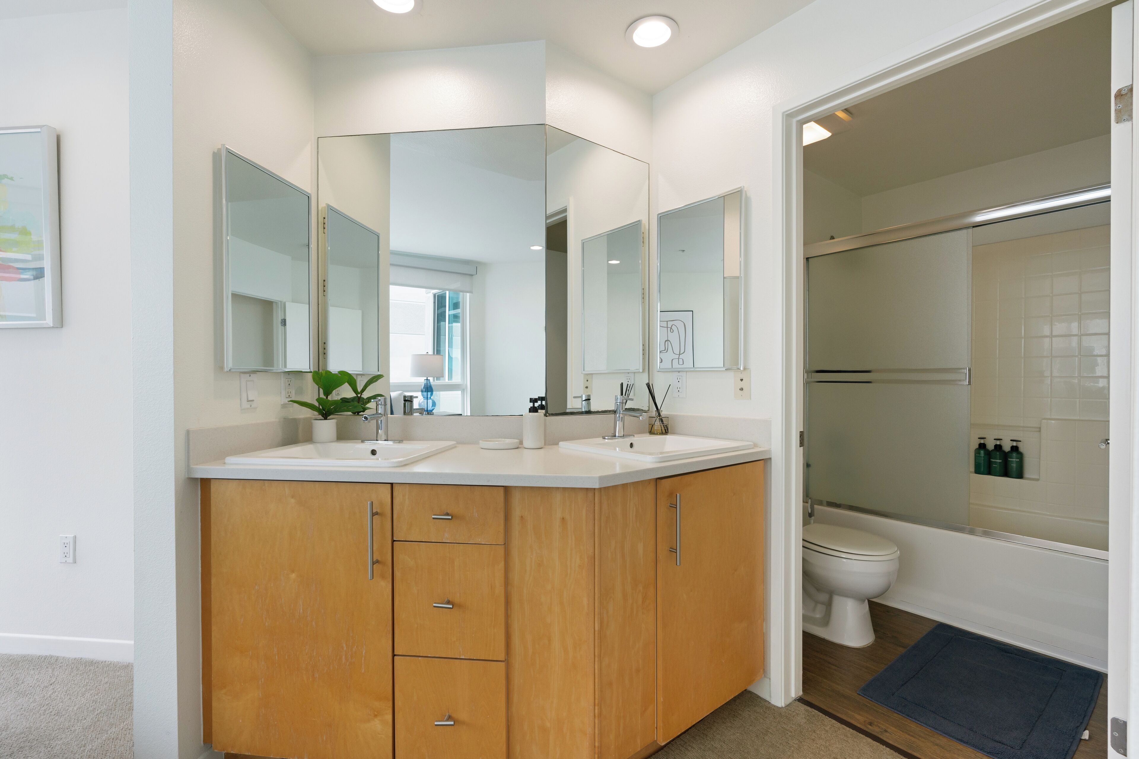 A bathroom with a double sink vanity, a mirror, a toilet, and a shower area.