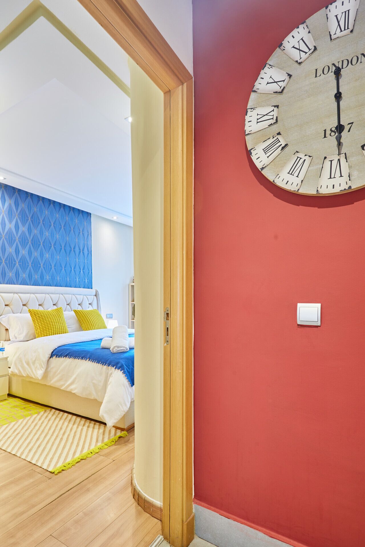 Um quarto com uma cama, uma mesinha de cabeceira e um relógio de parede.
