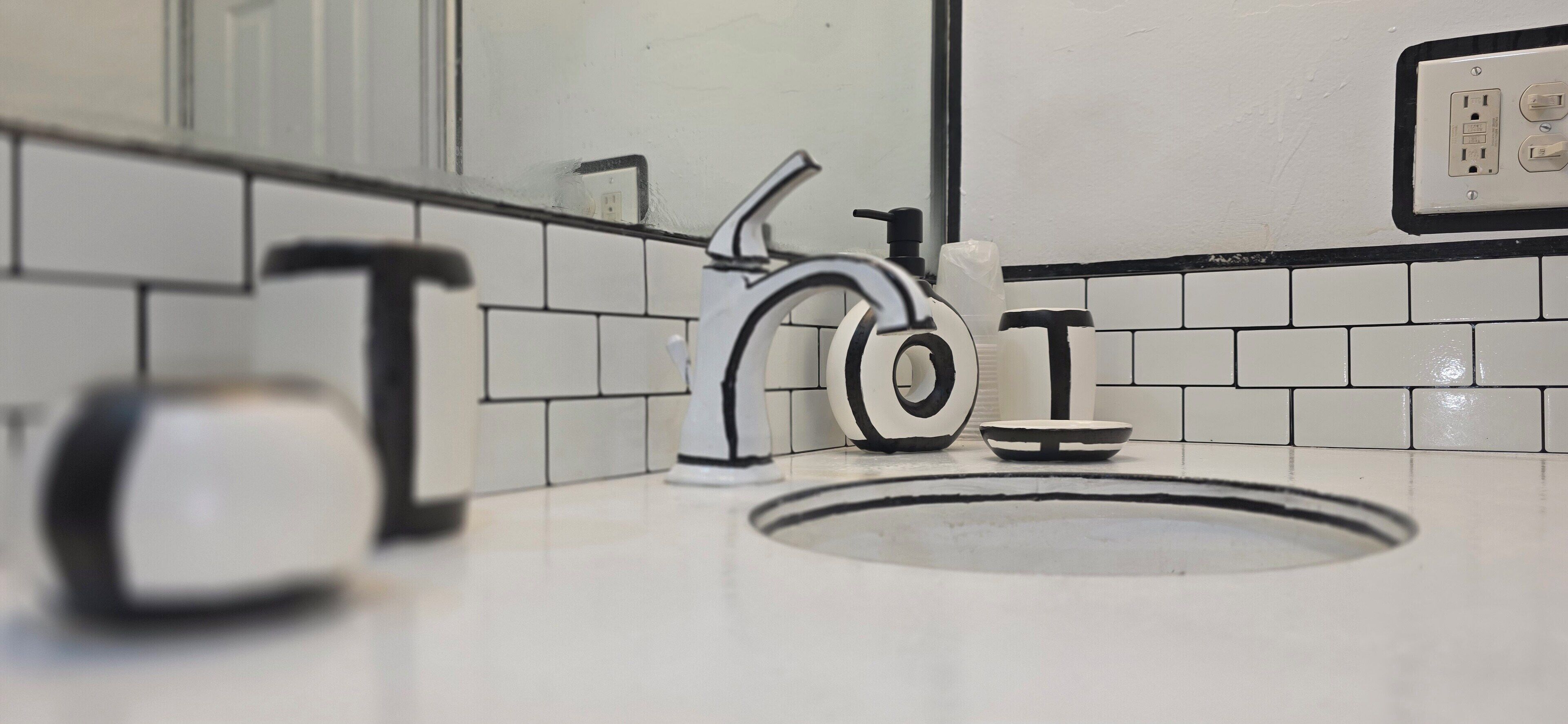 A bathroom with a white sink, a faucet, a soap dispenser, and a hand soap bottle.