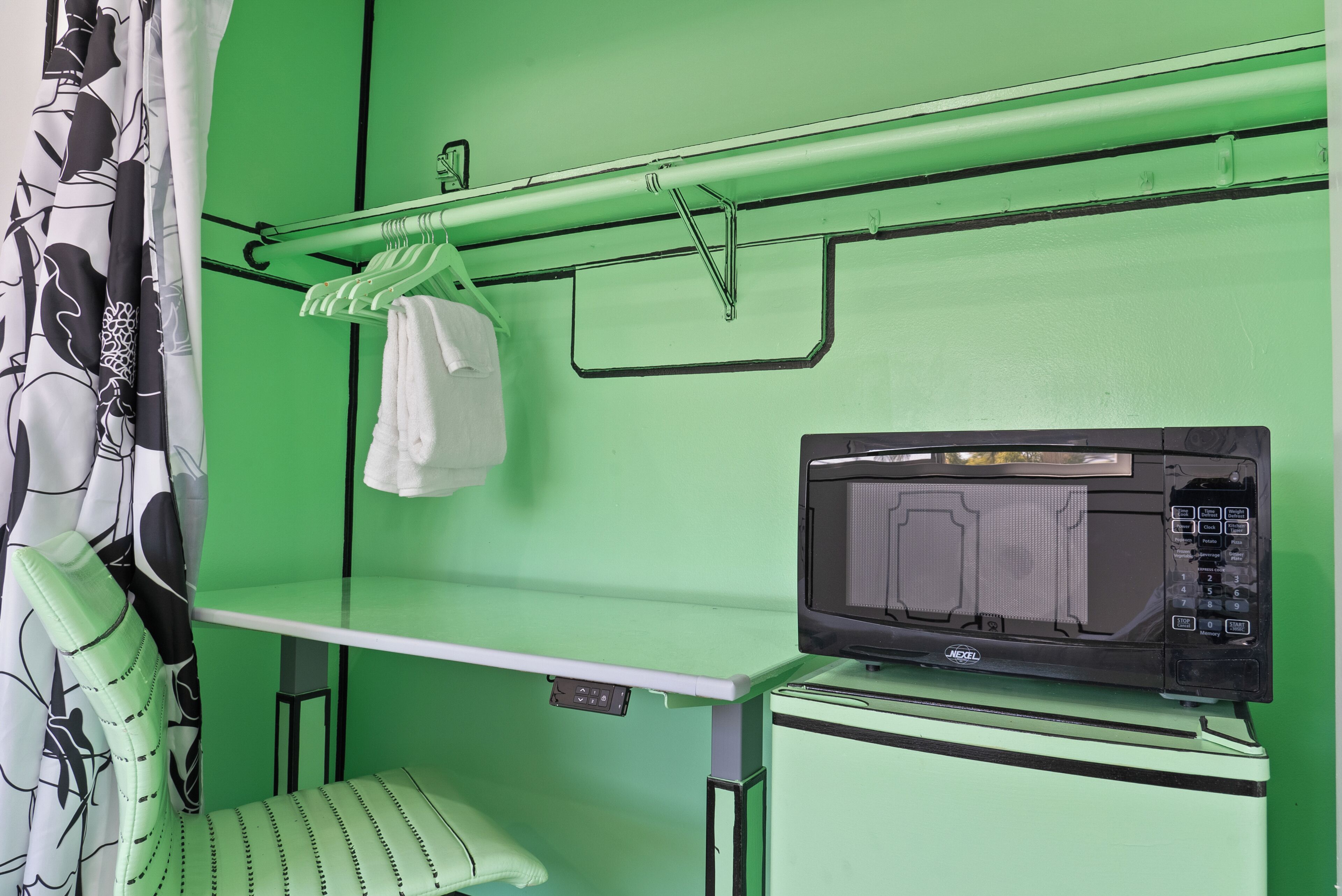 Una habitación verde con microondas, un banco y un perchero.