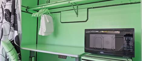 A green room with a microwave, a bench, and a towel rack.