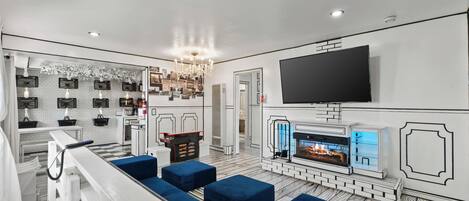 Una sala de estar moderna con chimenea, televisor de pantalla plana y otomanas azules.