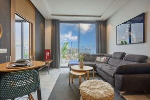 Una sala de estar moderna con un sofá, una mesa de comedor, una pequeña mesa de centro y un balcón con vistas.