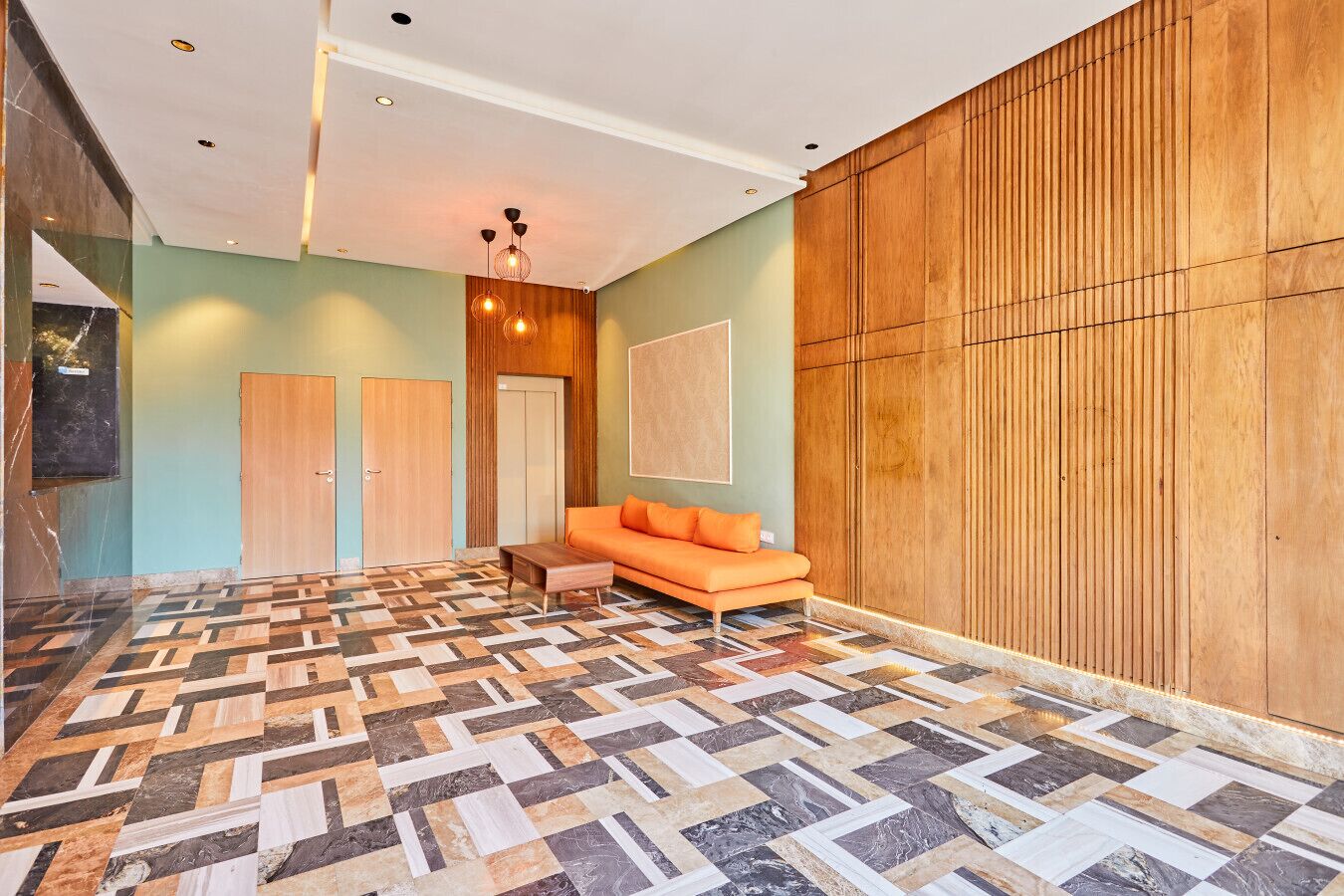 Eine Hotelhalle mit einem gemusterten Boden, einer Couch, einer Holzwandverkleidung und einer Tür.