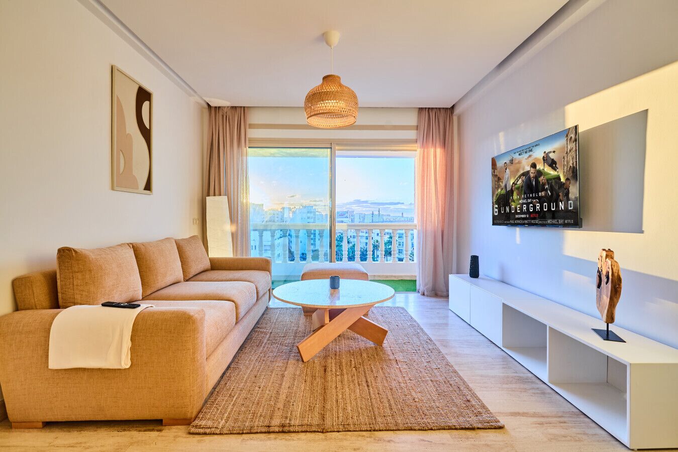 A modern living room with a sofa, a round table, and a TV mounted on the wall.