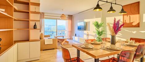 A modern dining area with a wooden table, clear chairs, and a city view.