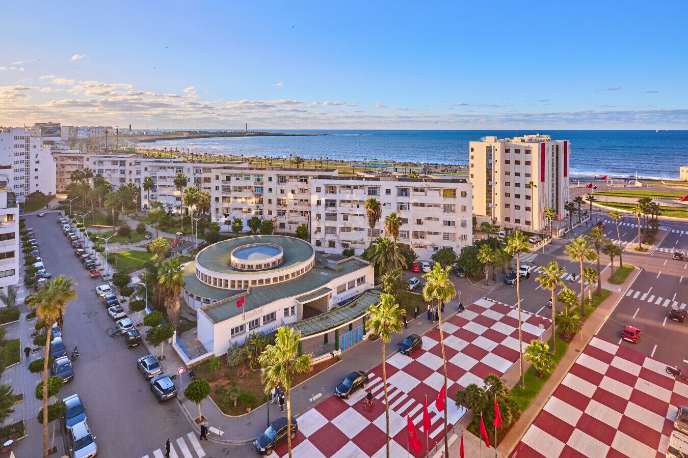 Ein Hotel an der Küste mit einem zentralen, kreisförmigen Innenhof, mehreren Etagen und Blick aufs Meer.
