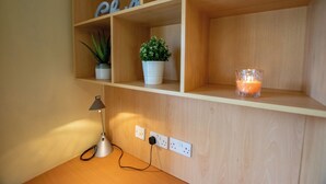 A wooden shelf with two potted plants, a glass candle holder, and a desk lamp. - Stunning Duplex By Shortstays (Galway)