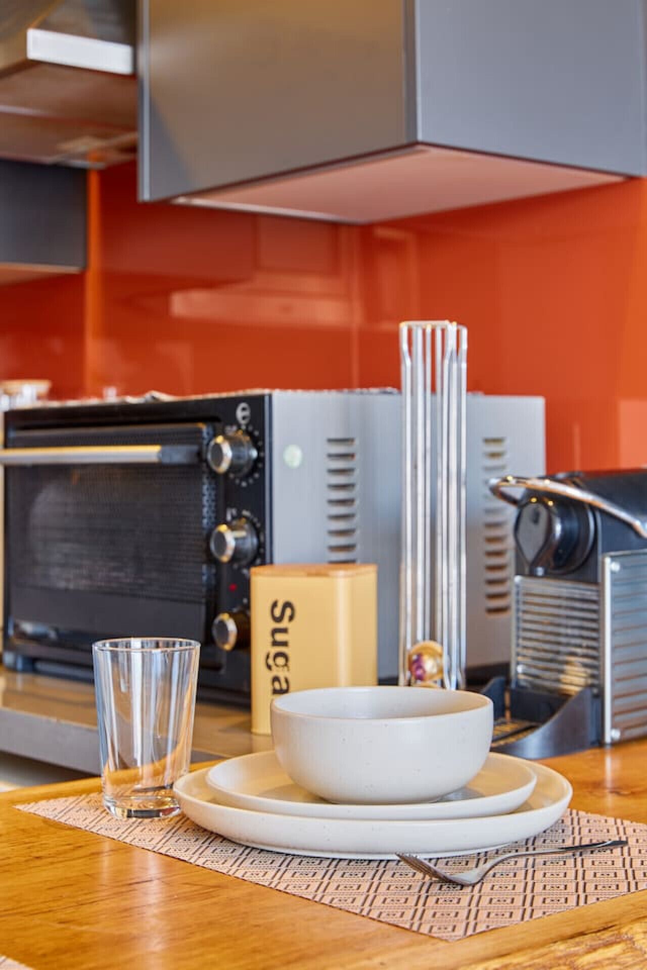 Een keuken met een magnetron, broodrooster en een glas water op het aanrecht.