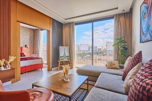 A modern hotel room with a large balcony, a bed, a sofa, a coffee table, and a painting of the Eiffel Tower. - Le loft du soleil B living (Casablanca)