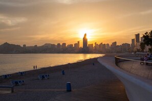 A waterfront promenade with a city skyline in the background during sunset.