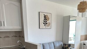 A modern kitchen with a dining area, white cabinetry, a hanging light fixture, and a wall-mounted artwork.