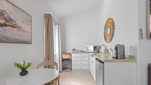Ett modernt kök med ett matbord, stolar, en mikrovågsugn och en kaffebryggare.