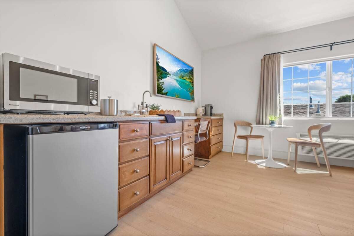 A modern kitchen with a built-in microwave, a dishwasher, wooden cabinets, and a dining area with a table and chairs.