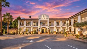 Un hotel con ingresso centrale, diversi balconi e un cartello che recita 'Bella Notte'.