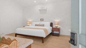 Una camera da letto con un letto, comodini, un condizionatore, una lampada a parete e una porta con serratura a codice.