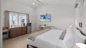 A bedroom with a bed, bedside table, and a window with curtains. - Bella Notte by the beach Studio 8 (Pleasure Point)