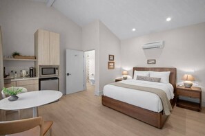 A modern bedroom with a bed, bedside tables, a small desk, and a kitchenette. - Bella Notte, a ZenStay Hotel - Studio 7 (Pleasure Point)