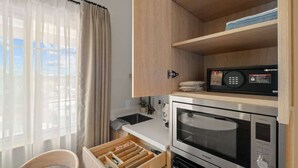 A compact kitchen with a microwave, oven, and wooden cabinets. - Bella Notte by the beach Studio 7 (Pleasure Point)