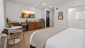 Une chambre d’hôtel de taille réduite comprenant un lit, une petite kitchenette, un coin repas et une salle de bain.