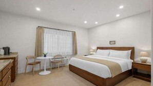 Ein Hotelzimmer mit Bett, Nachttisch, Lampe und einem kleinen Tisch mit Stühlen.