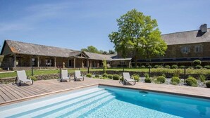 A pool with lounge chairs, a stone building, and a large tree. - Hotel de l Abbaye Le Tronchet Saint Malo (Le Tronchet)