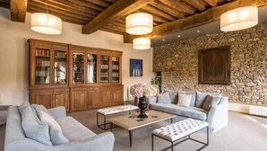 A spacious living room with a stone wall, wooden bookshelves, and a high ceiling with exposed beams. - Hotel de l Abbaye Le Tronchet Saint Malo (Le Tronchet)