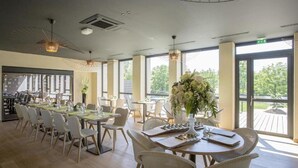 A spacious dining area with high ceilings, large windows, and wicker furniture. - Hotel de l Abbaye Le Tronchet Saint Malo (Le Tronchet)