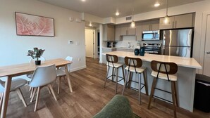 Une cuisine moderne avec un coin repas, un plancher en bois et des luminaires suspendus.