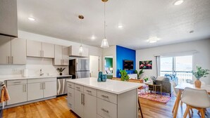 Una cocina moderna con armarios blancos, una isla central y un comedor con mesa y sillas.