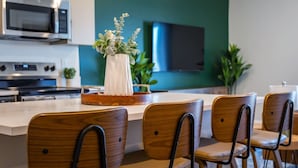 Eine moderne Küche mit einer zentralen Kochinsel, Holzkreisen, einer Mikrowelle, einem Backofen und einem Flachbildfernseher.