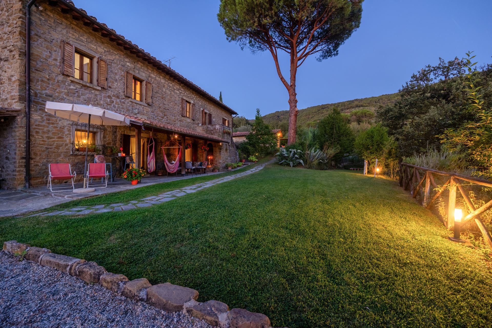 A stone building with a patio area, outdoor seating, and a well-maintained lawn.