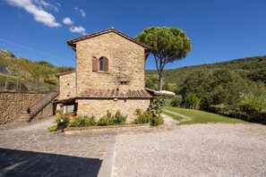 A stone building with a small window and a door, surrounded by a gravel driveway and a grassy area. - Agriturismo Antica Quercia Verde - Gonfianuvole (Cortona)