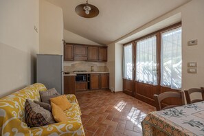 Une cuisine compacte avec des meubles en bois, un four encastré et un coin repas comprenant une table et des chaises.