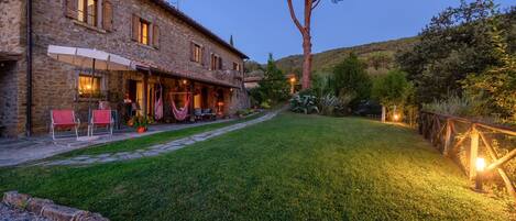 A stone building with a patio area, outdoor seating, and a well-maintained lawn.