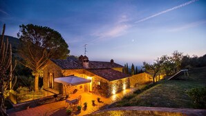 Un edificio in pietra con tetto a tegole, posti a sedere all'aperto e una scala che conduce all'interno.