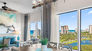 A modern dining area with a view of a cityscape and water. - Luau I 7010/7012 - Sunset Suite (Miramar Beach)