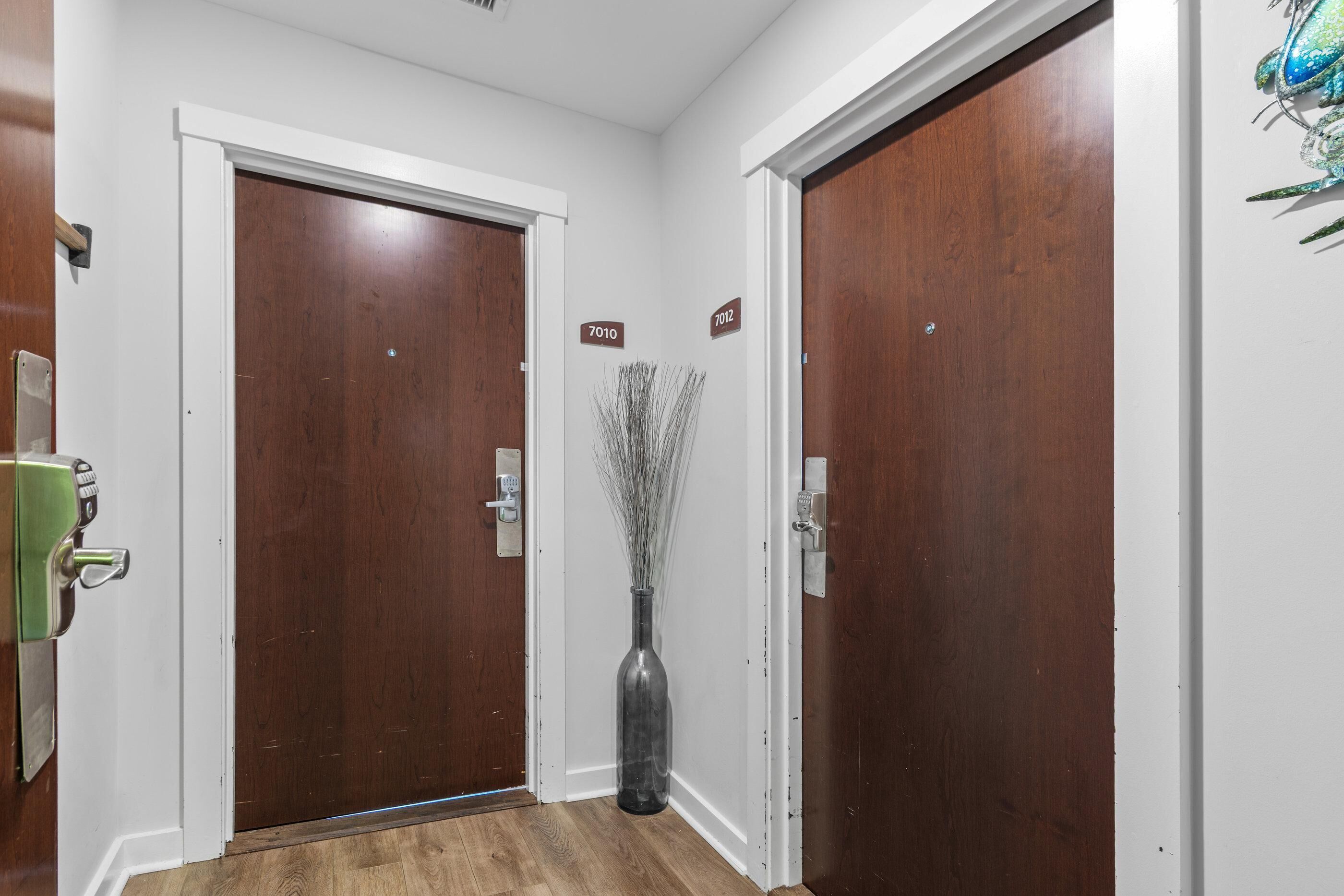 A hallway with two wooden doors, each marked with a number sign, and a vase with branches in the center.