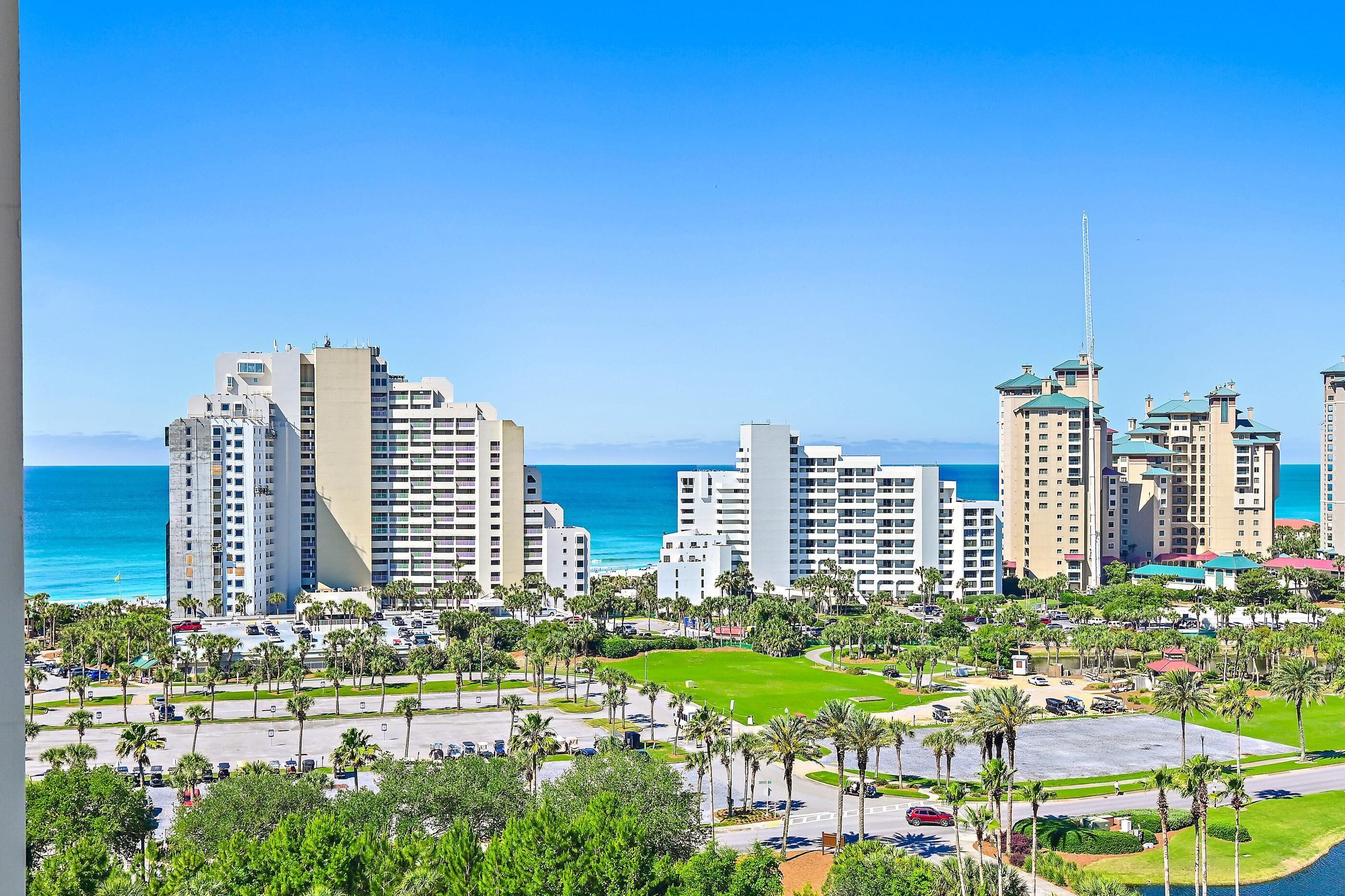 A coastal cityscape with high-rise buildings, a clear blue sky, and a view of the ocean.