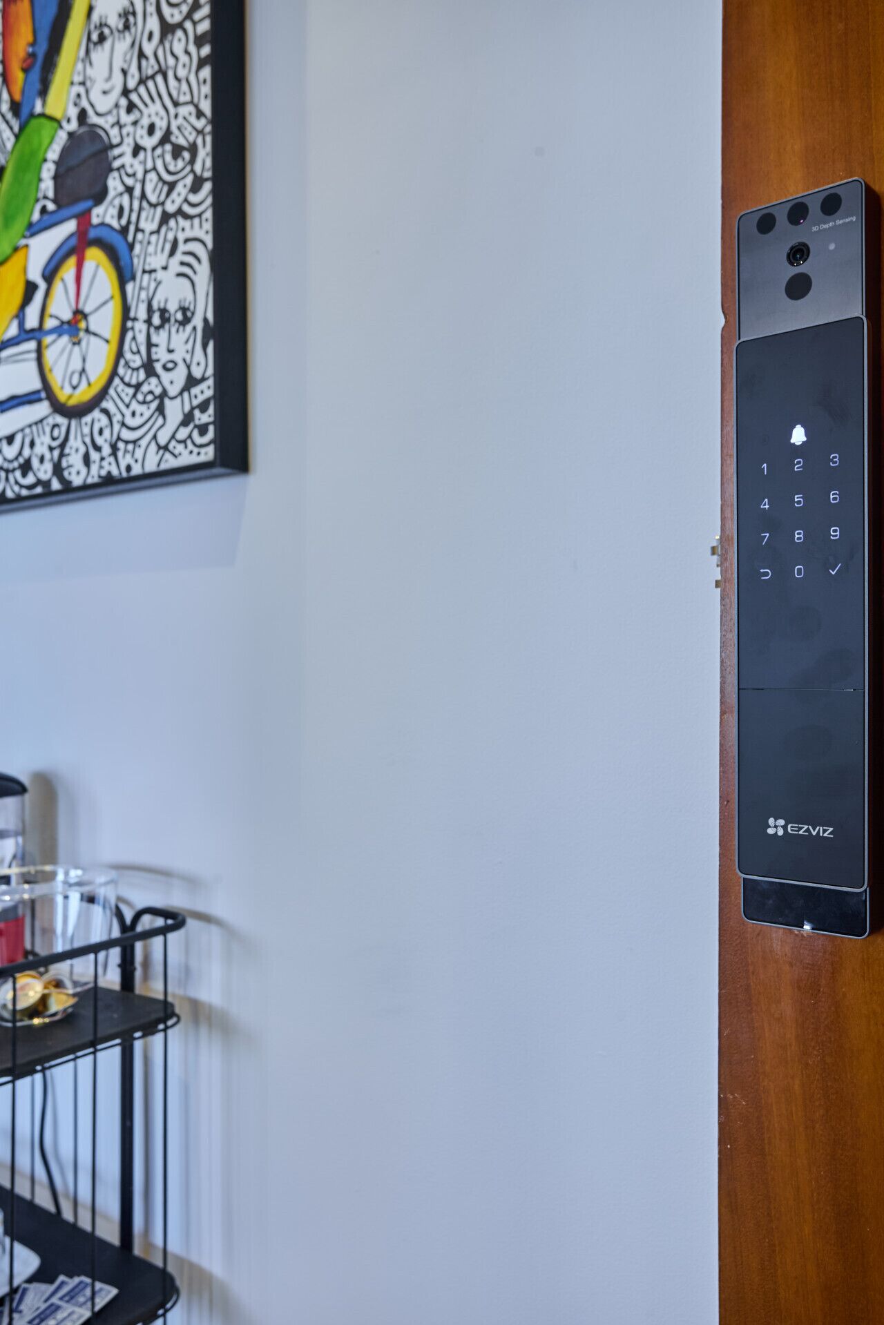 A 3D door lock with a keypad, a framed abstract painting, and a small table with a tray.