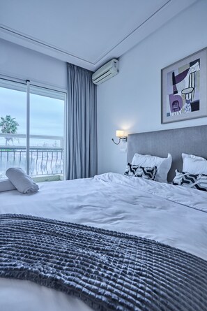 A hotel room with a large bed, a view through the window, and a painting on the wall. - Sunny & Spacious 3 BR Apartment - CIL view (Casablanca)
